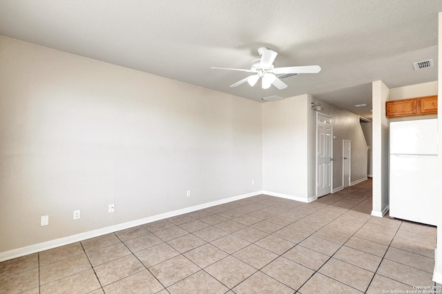 spare room with light tile patterned floors, visible vents, ceiling fan, a textured ceiling, and baseboards