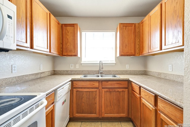 kitchen featuring white appliances, light tile patterned floors, brown cabinets, light countertops, and a sink