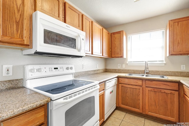 kitchen with white appliances, light countertops, a sink, and light tile patterned flooring