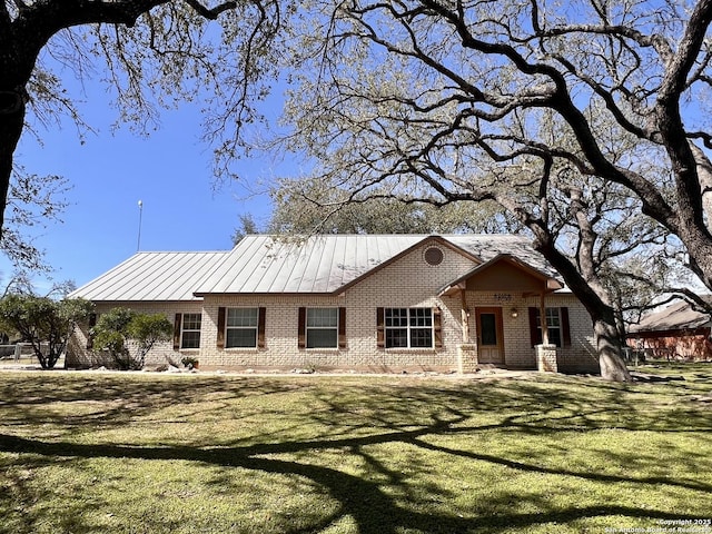 ranch-style home featuring a standing seam roof, brick siding, and a front yard