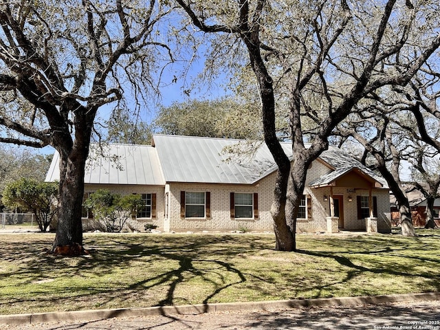 cape cod home featuring a standing seam roof, metal roof, brick siding, and a front lawn