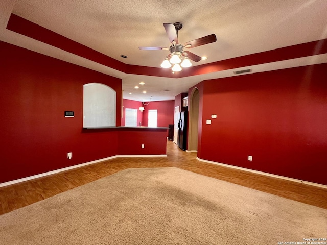 carpeted spare room featuring baseboards, visible vents, a textured ceiling, and wood finished floors