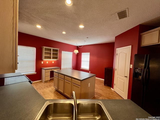 kitchen with a sink, light wood finished floors, visible vents, and black fridge