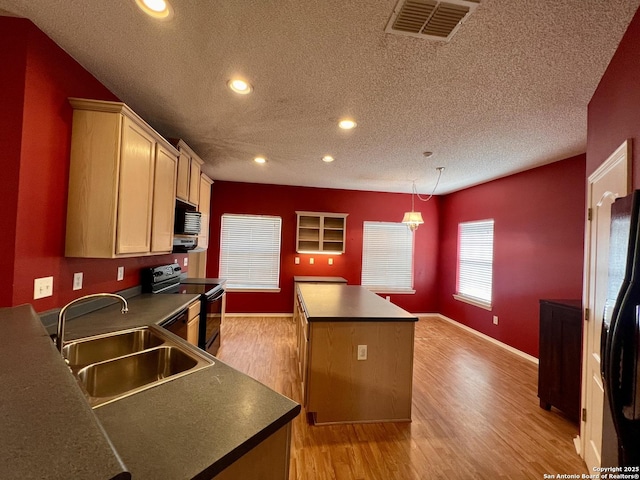 kitchen featuring black appliances, a kitchen island, dark countertops, and a sink