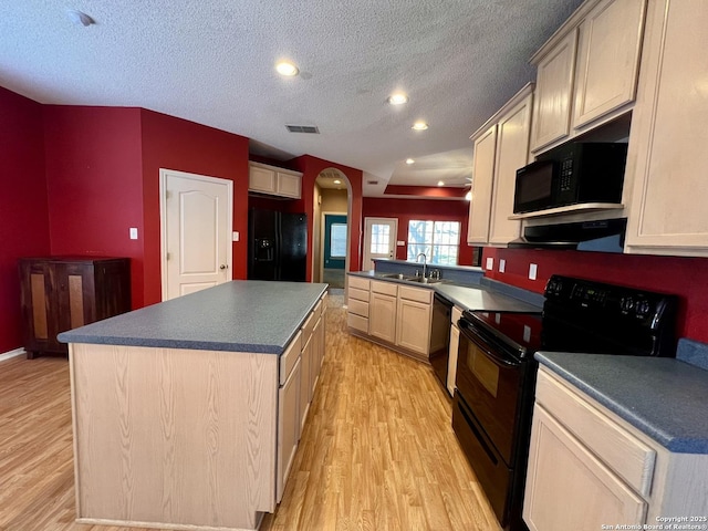 kitchen featuring visible vents, dark countertops, light wood-style flooring, black appliances, and a sink