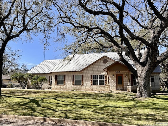 ranch-style home with a standing seam roof, a front yard, metal roof, and brick siding