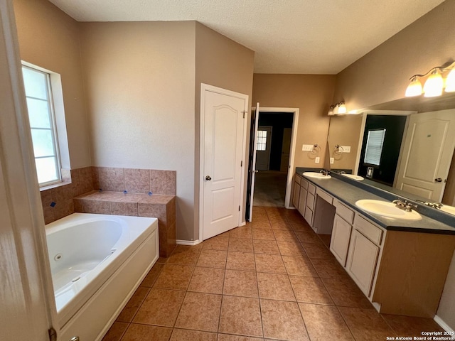 full bathroom featuring a whirlpool tub, double vanity, tile patterned flooring, and a sink