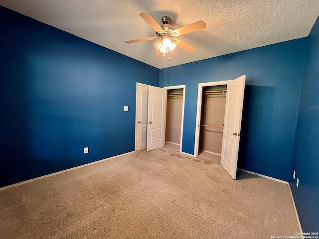 unfurnished bedroom featuring multiple closets, a ceiling fan, carpet flooring, a textured ceiling, and baseboards