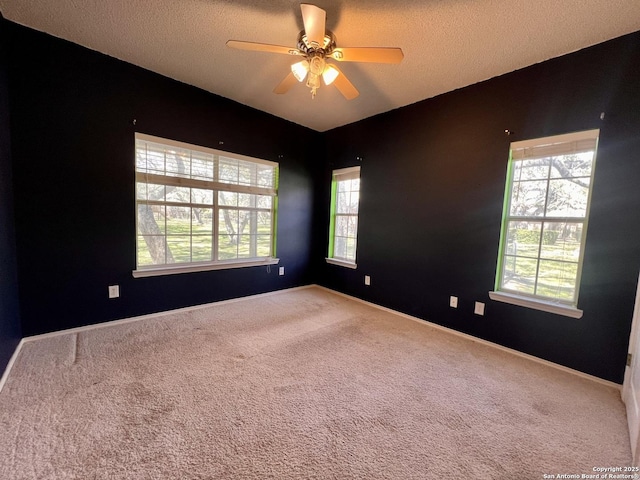 carpeted spare room featuring a textured ceiling, a ceiling fan, and a wealth of natural light