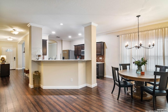 dining area featuring an inviting chandelier, baseboards, dark wood finished floors, and crown molding