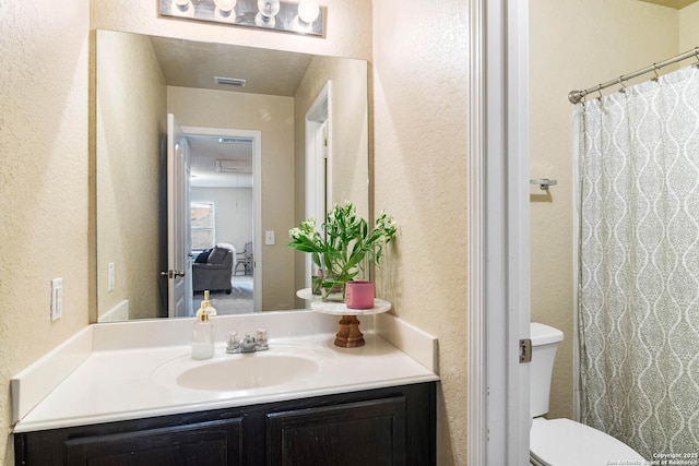 full bath with toilet, a textured wall, vanity, and visible vents