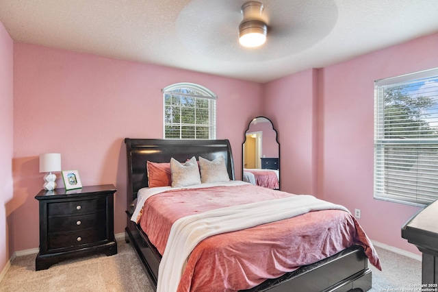 bedroom with a ceiling fan, baseboards, a textured ceiling, and light colored carpet