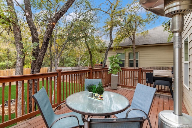 wooden deck with outdoor dining area, fence, and a lawn