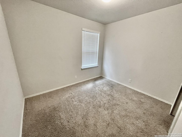 carpeted spare room featuring baseboards and a textured ceiling