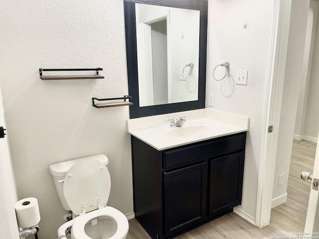 bathroom featuring toilet, wood finished floors, vanity, and baseboards