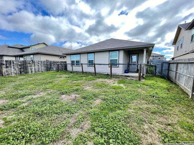 rear view of house with a lawn and a fenced backyard