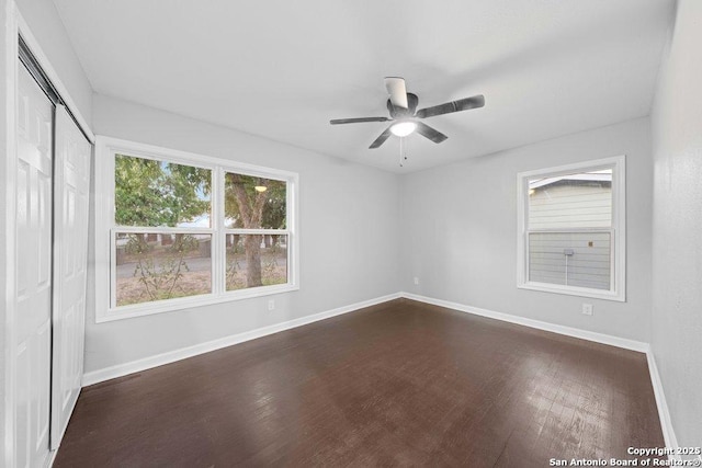 empty room featuring ceiling fan, baseboards, and dark wood-type flooring