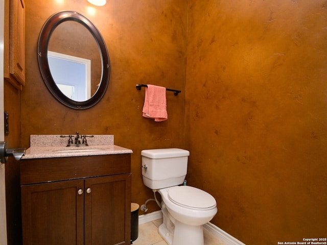 half bathroom featuring toilet, vanity, baseboards, and tile patterned floors