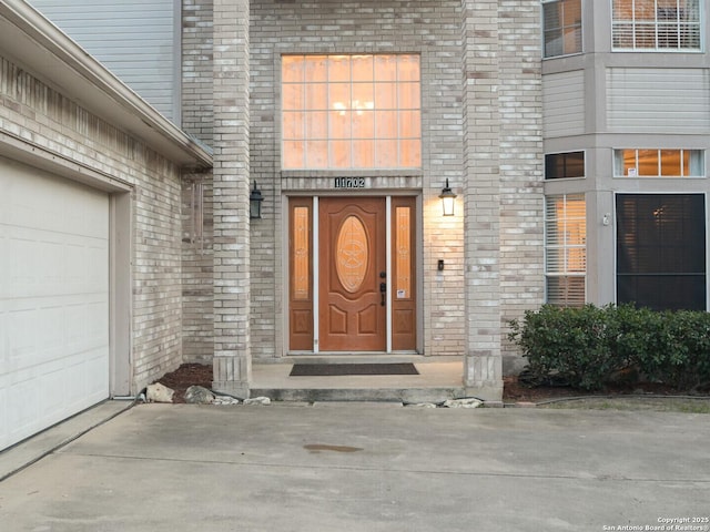 entrance to property with a garage and brick siding