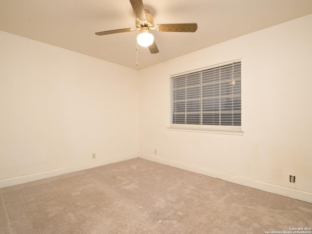 carpeted spare room featuring a ceiling fan and baseboards