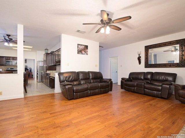 living room featuring ceiling fan, light wood-style flooring, and visible vents