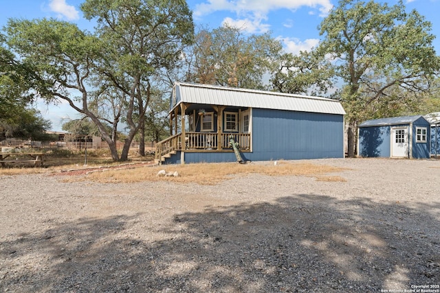 view of front of home featuring a shed, a porch, and an outdoor structure