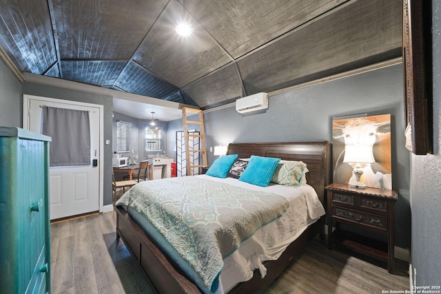 bedroom featuring lofted ceiling, baseboards, wood finished floors, and a wall mounted AC