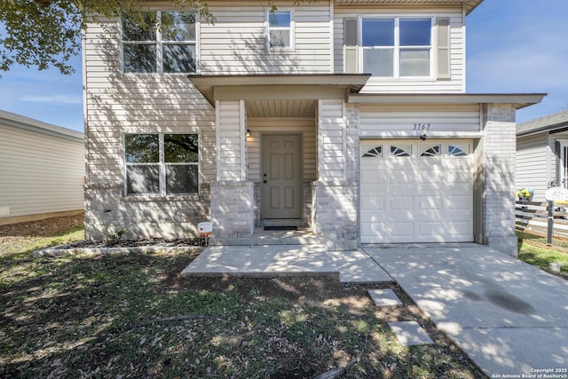 view of front of home with an attached garage, concrete driveway, and brick siding