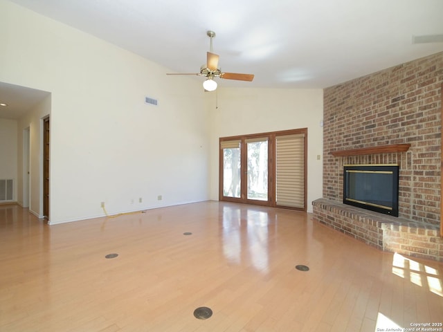 unfurnished living room featuring ceiling fan, a brick fireplace, wood finished floors, and visible vents