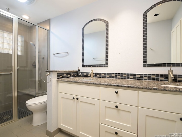 bathroom with double vanity, a stall shower, a sink, and toilet