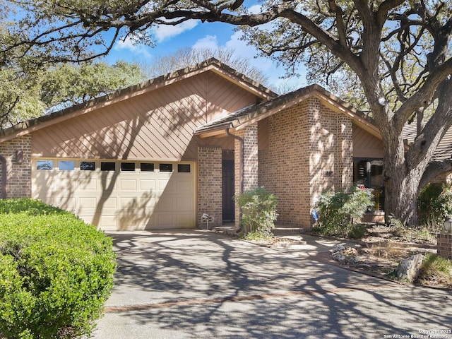 view of side of home with a garage, driveway, and brick siding