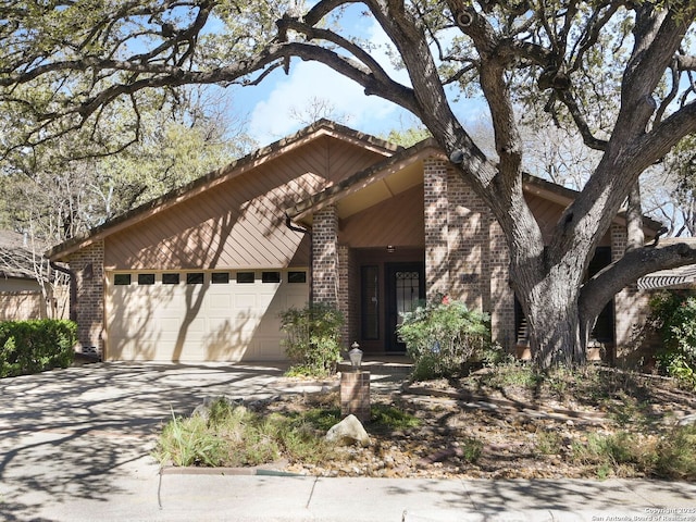 mid-century inspired home featuring an attached garage, concrete driveway, and brick siding