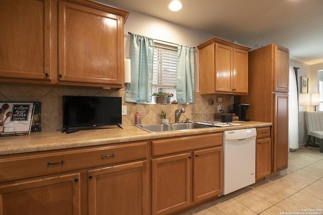 kitchen with light tile patterned floors, tasteful backsplash, white dishwasher, and a sink