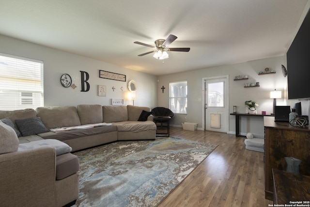 living area featuring a ceiling fan, baseboards, and wood finished floors