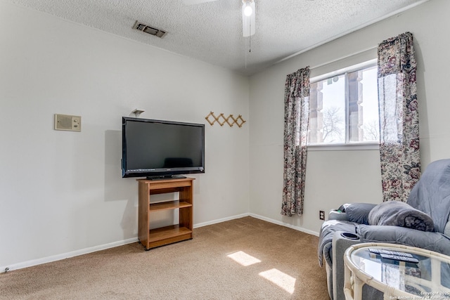 sitting room with a textured ceiling, carpet, visible vents, and baseboards