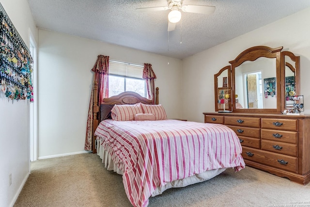 bedroom with a ceiling fan, light carpet, a textured ceiling, and baseboards