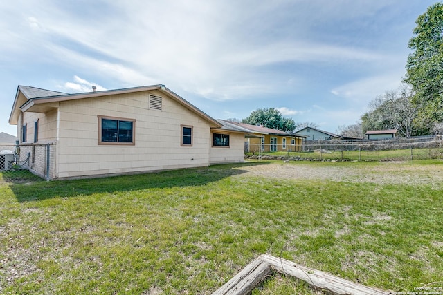 rear view of house featuring a yard, central AC unit, and fence