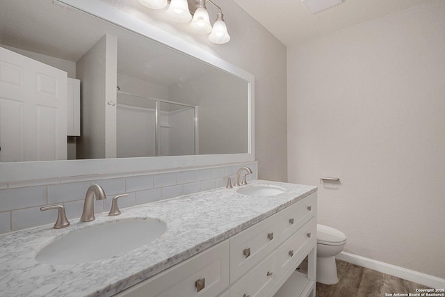 bathroom with wood finished floors, a stall shower, a sink, and baseboards