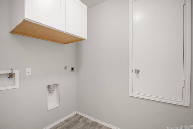 clothes washing area featuring cabinet space, baseboards, wood finished floors, hookup for a washing machine, and electric dryer hookup