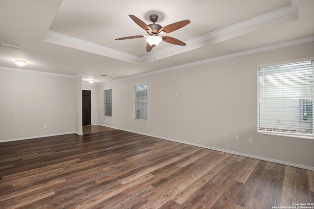 spare room featuring wood finished floors, a ceiling fan, baseboards, a tray ceiling, and crown molding