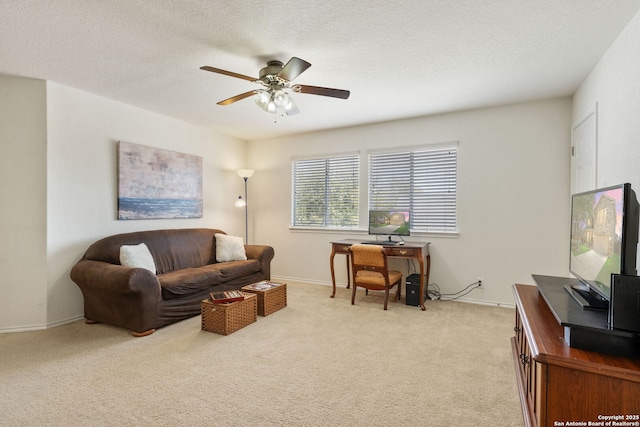 living area with baseboards, light carpet, a textured ceiling, and a ceiling fan