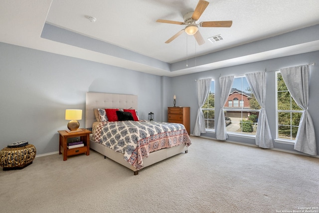 bedroom featuring visible vents, a ceiling fan, baseboards, carpet floors, and a raised ceiling