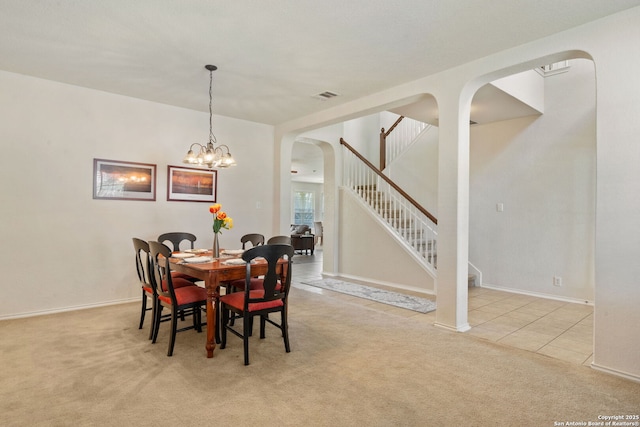 dining area featuring visible vents, carpet floors, arched walkways, baseboards, and stairs