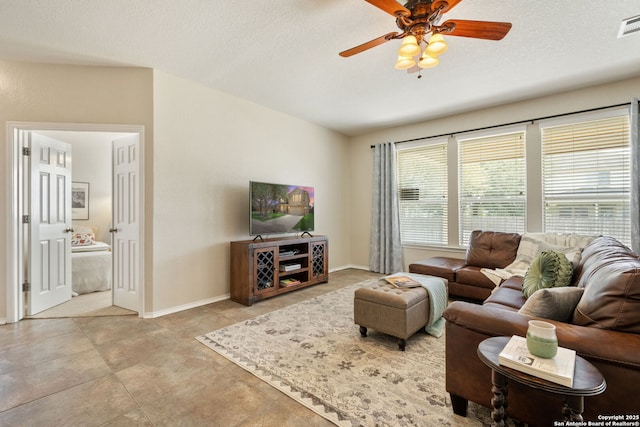 living room with baseboards, visible vents, a textured ceiling, and ceiling fan