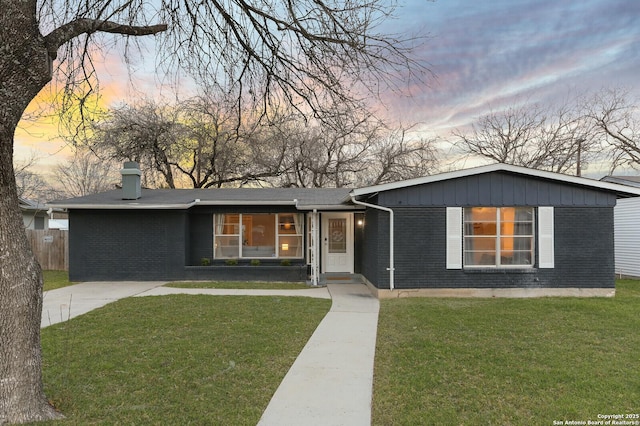 view of front of home featuring a yard, brick siding, and fence