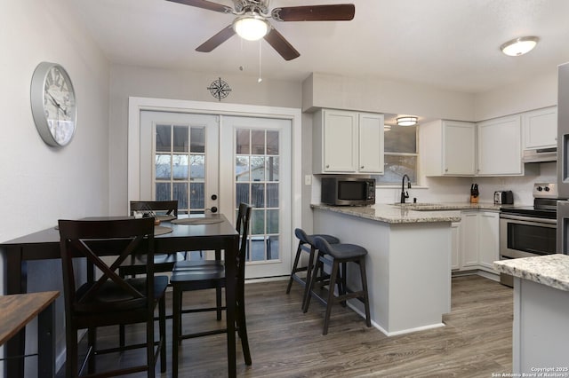 kitchen with white cabinets, stainless steel appliances, wood finished floors, and french doors