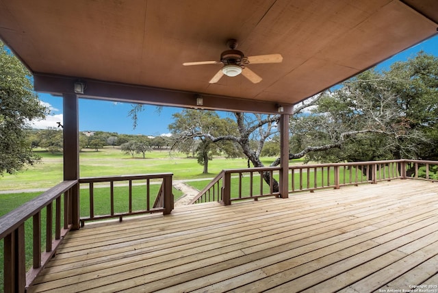 wooden terrace with a ceiling fan and a yard