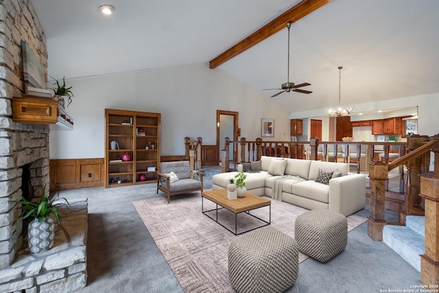 living room featuring a wainscoted wall, beamed ceiling, a stone fireplace, carpet floors, and high vaulted ceiling