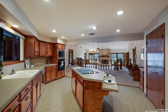 kitchen featuring a sink, visible vents, light countertops, a center island, and black appliances