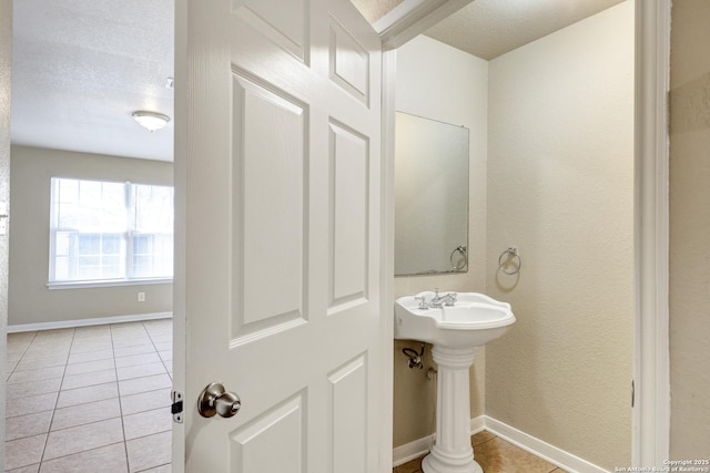 bathroom with baseboards, a textured ceiling, and tile patterned floors